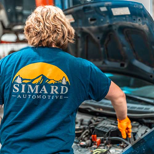 Mechanic working on car engine, Simard Automotive logo.