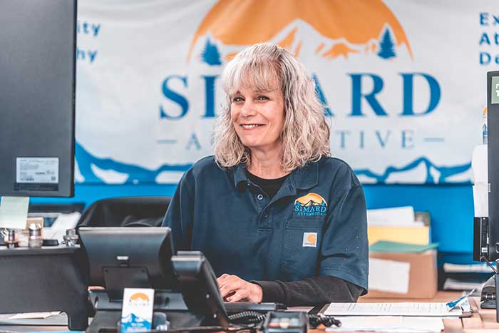 Smiling employee at office desk, Simard Automotive.