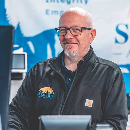 Smiling bald man in black jacket and glasses.